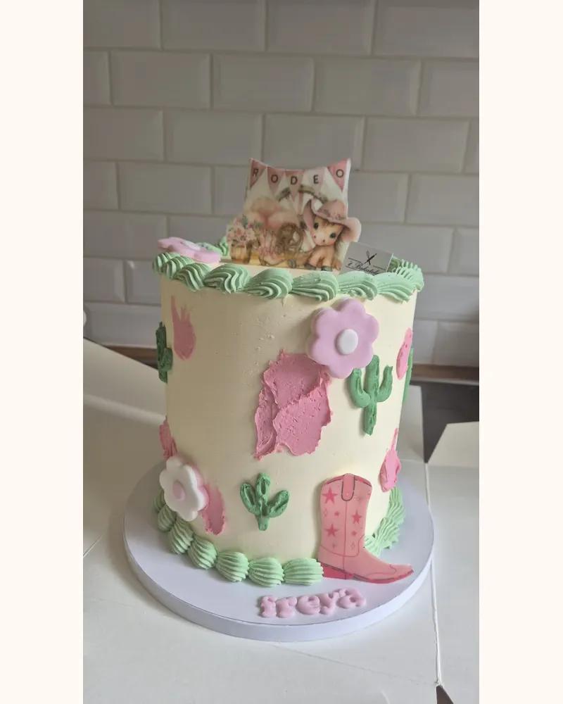 Pastelkleurige taart met cactussen, bloemen en een cowboylaarsje